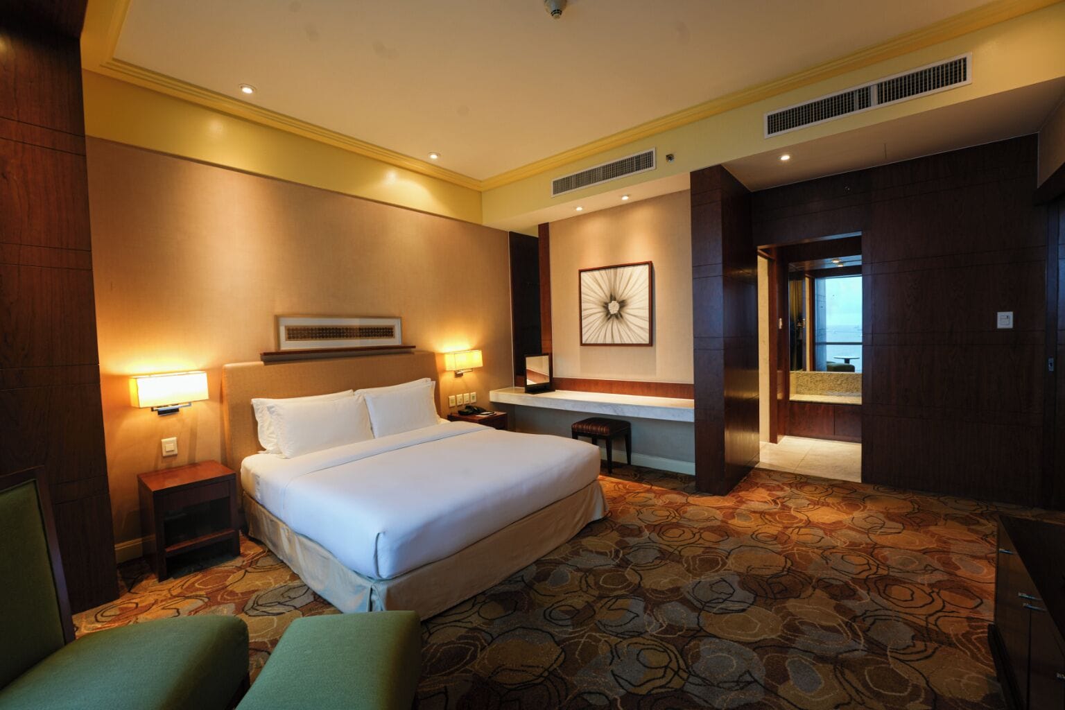 A hotel room with a large bed, bedside tables, a desk, and a view of the ocean.