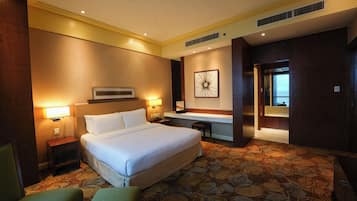 A hotel room with a large bed, bedside tables, a desk, and a view of the ocean.