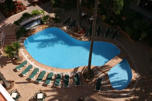 Vista aérea de una piscina con sillas de descanso y una pequeña cascada.