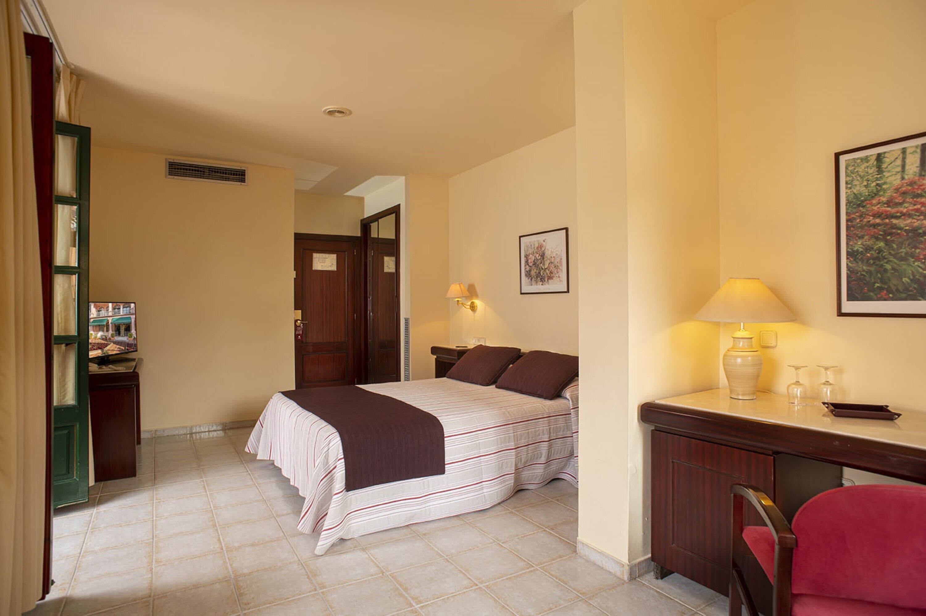 Una habitación de hotel con cama, mesita de noche, lámpara y una silla.