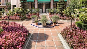 Un hotel con un patio central, varios balcones y un toldo verde sobre la entrada.