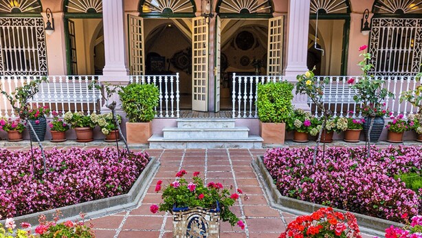 Un patio con una fuente, plantas en macetas y un edificio con balcón.