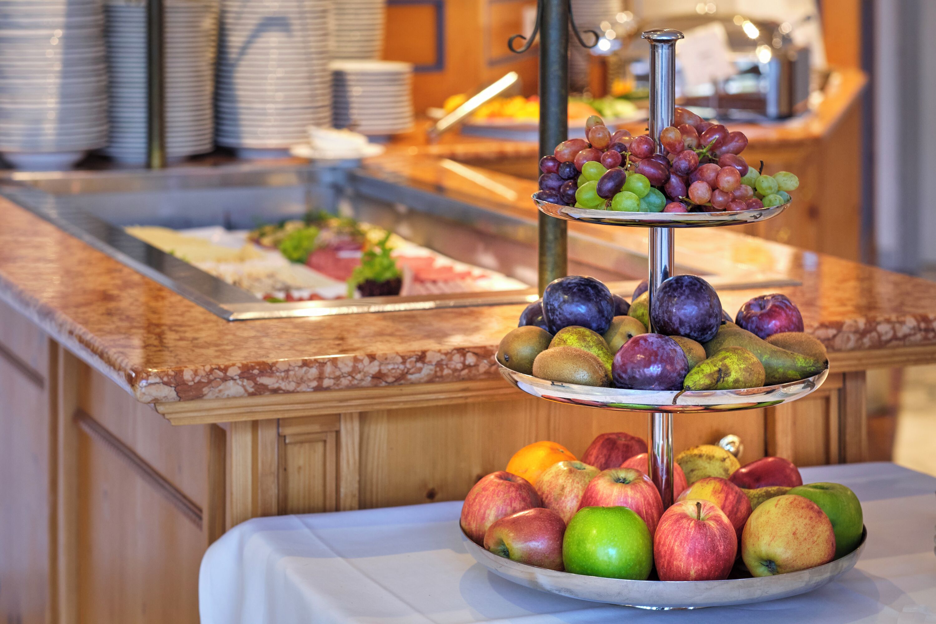 A buffet with a variety of fruits and a three-tiered fruit display.
