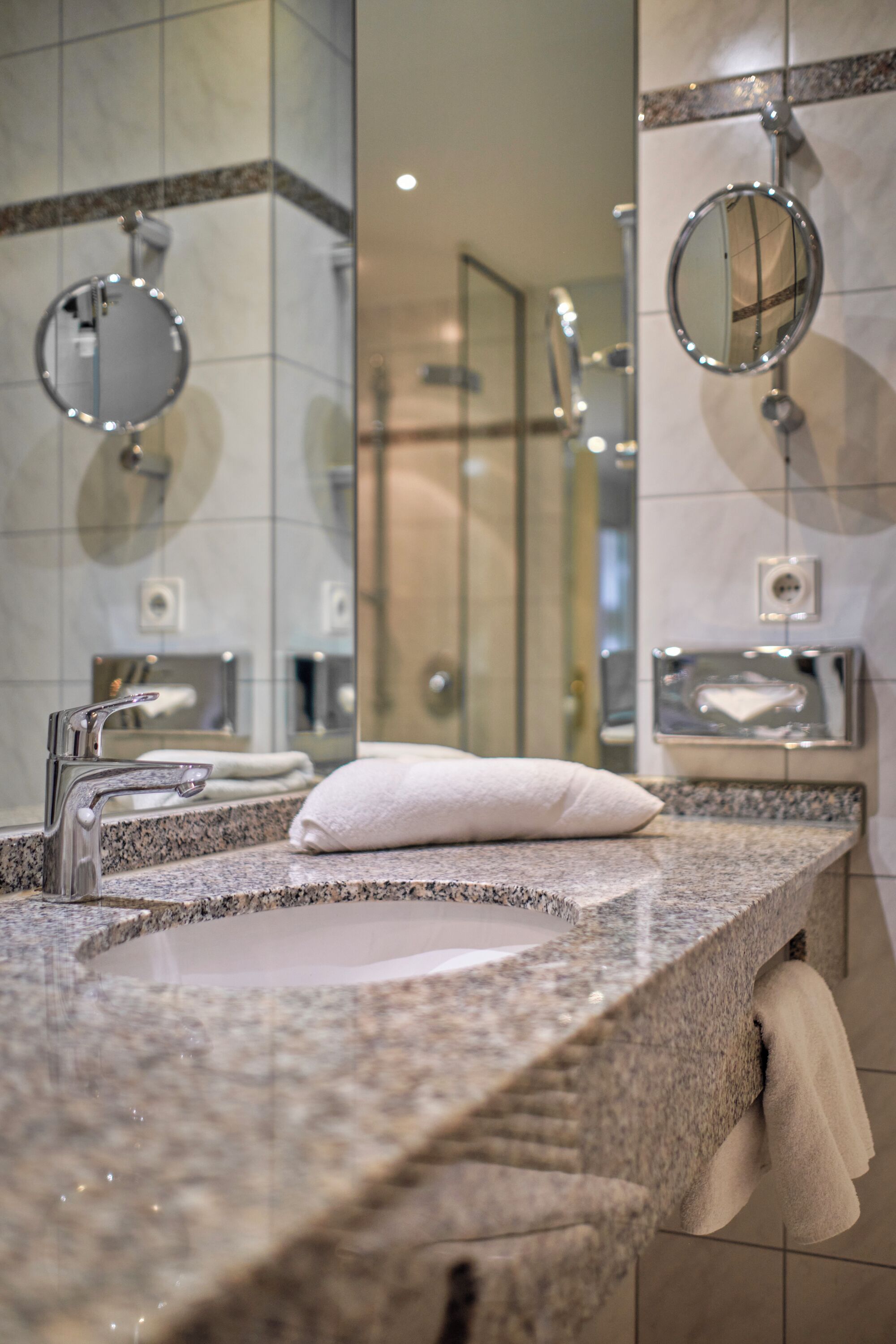 Une salle de bain avec un comptoir en granit, un lavabo, un miroir et un porte-serviettes.