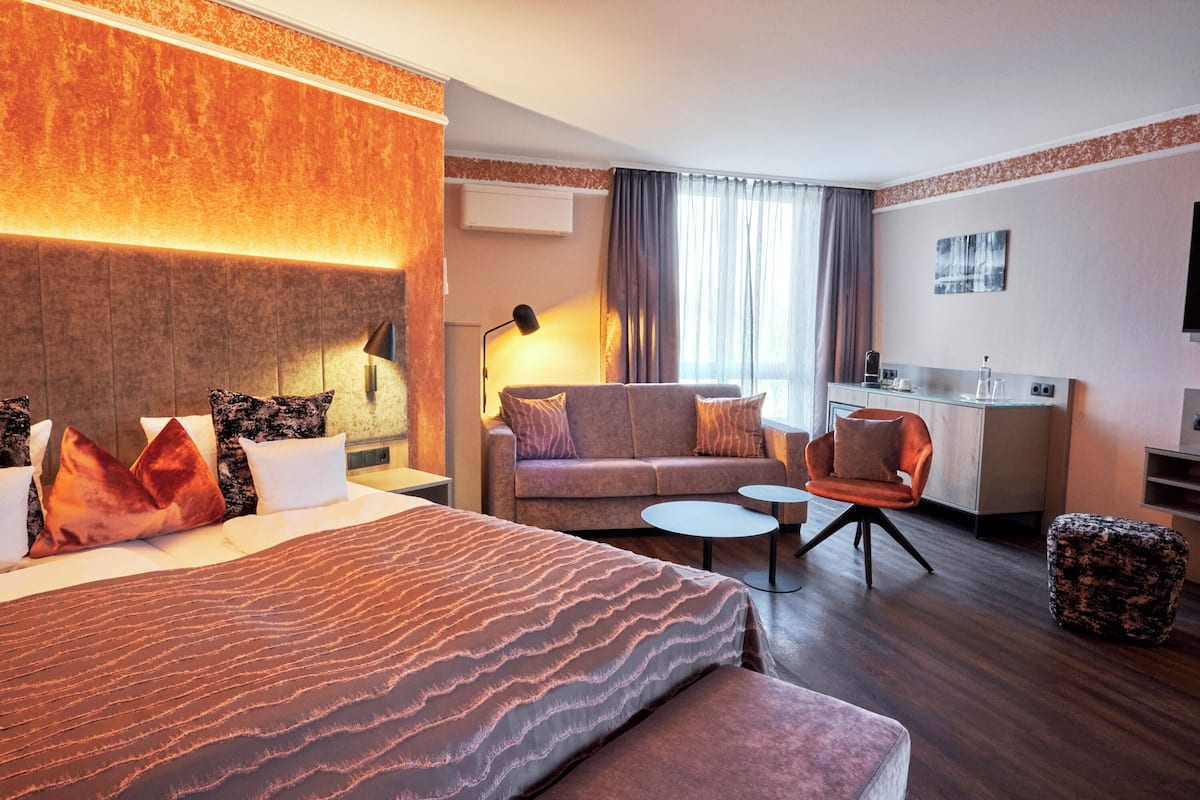 Een hotelkamer met een groot bed, een sofa, een bureau en een stoel.