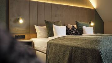 A modern bedroom with a wooden headboard, a bed with white and green bedding, and two wall-mounted reading lights.