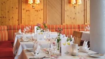 A restaurant with tables set for dining, featuring floral tablecloths and neatly arranged table settings.