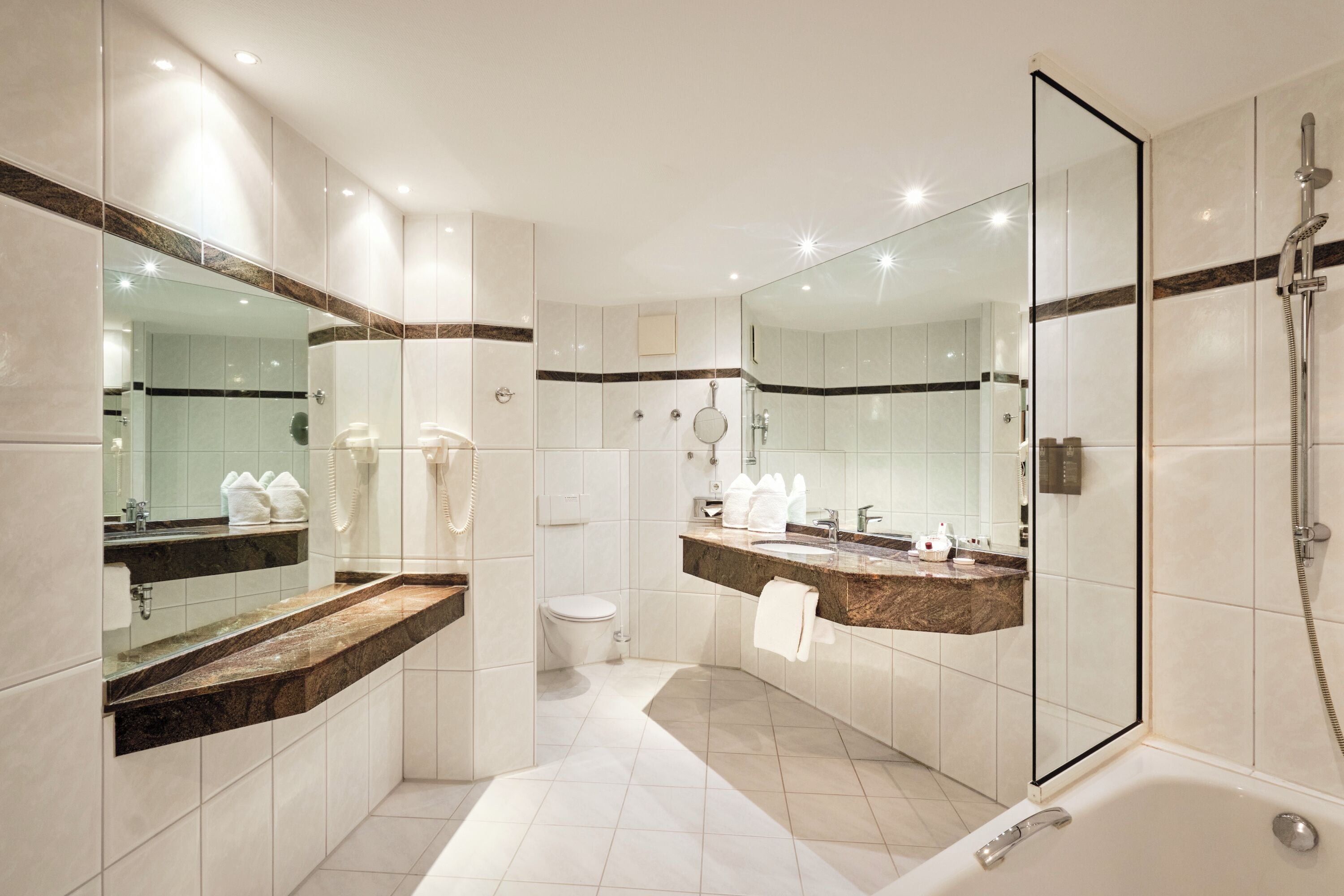 A modern bathroom with a glass-enclosed shower, a vanity with a marble countertop, and a large mirror.