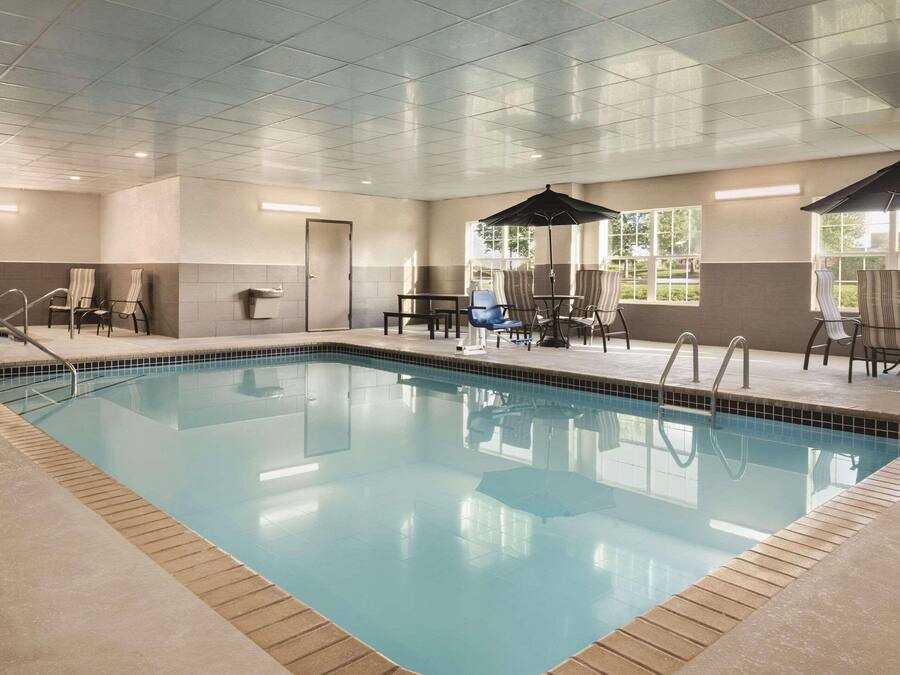 An indoor swimming pool with clear water, surrounded by lounge chairs and umbrellas, and a tiled ceiling.