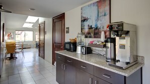 A kitchen with a coffee machine, microwave, toaster, and a large abstract painting on the wall. - Americas Best Value Inn Heath Newark (Heath)