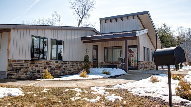 A modern building with a stone facade, large windows, and a snow-covered lawn. - Americas Best Value Inn Heath Newark (Heath)