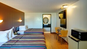A hotel room with two beds, a small table, a chair, a microwave, and a mirror. - Americas Best Value Inn Heath Newark (Heath)