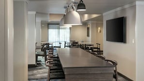 A conference room with a long table, chairs, pendant lights, and a flat-screen TV on the wall. - Fairfield Inn and Suites by Marriott Anchorage (Anchorage)