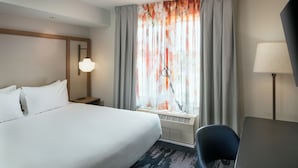 A hotel room with a large bed, a desk, a chair, a window with curtains, and a lamp. - Fairfield Inn and Suites by Marriott Anchorage (Anchorage)