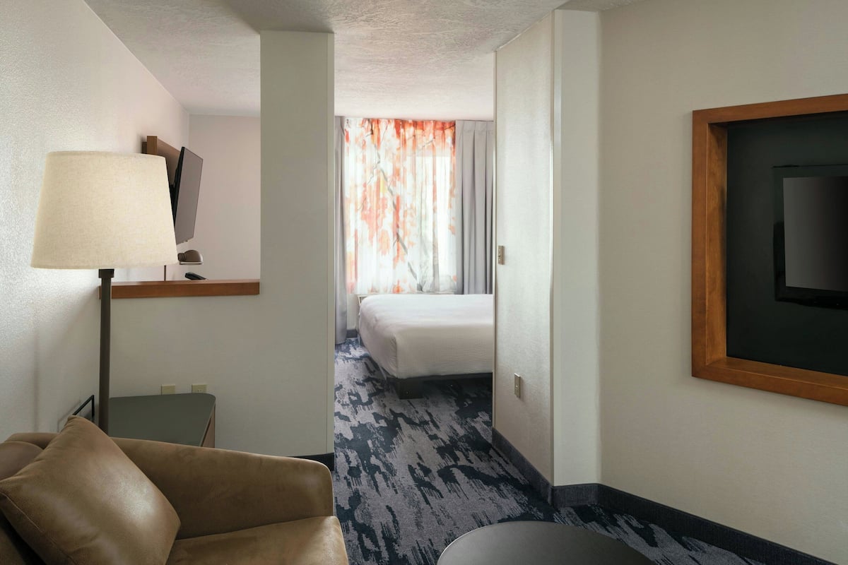 Une chambre d’hôtel avec un lit, un bureau, une chaise, une lampe et un téléviseur.