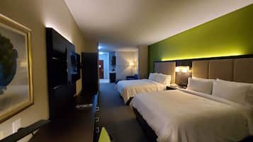 A hotel room with two beds, a TV, a desk, and a green accent wall.
