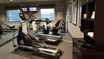 A gym with treadmills, stationary bikes, and a mirrored wall.