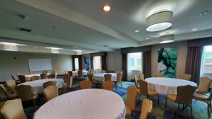 A conference room with multiple round tables, chairs, and a whiteboard.