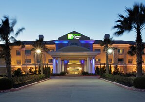 A Holiday Inn Express hotel with a central entrance, palm trees, and a clear sky. - Holiday Inn Express Hotel & Suites Pearland by IHG (Pearland)