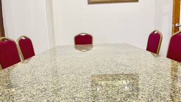 A conference room with a granite table and red upholstered chairs.