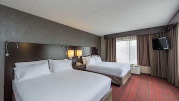 A hotel room with two beds, a flat-screen TV, a window with curtains, and a red carpeted floor.