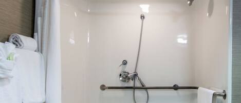 Une douche à l’italienne avec un banc, un porte-serviettes et une pomme de douche.