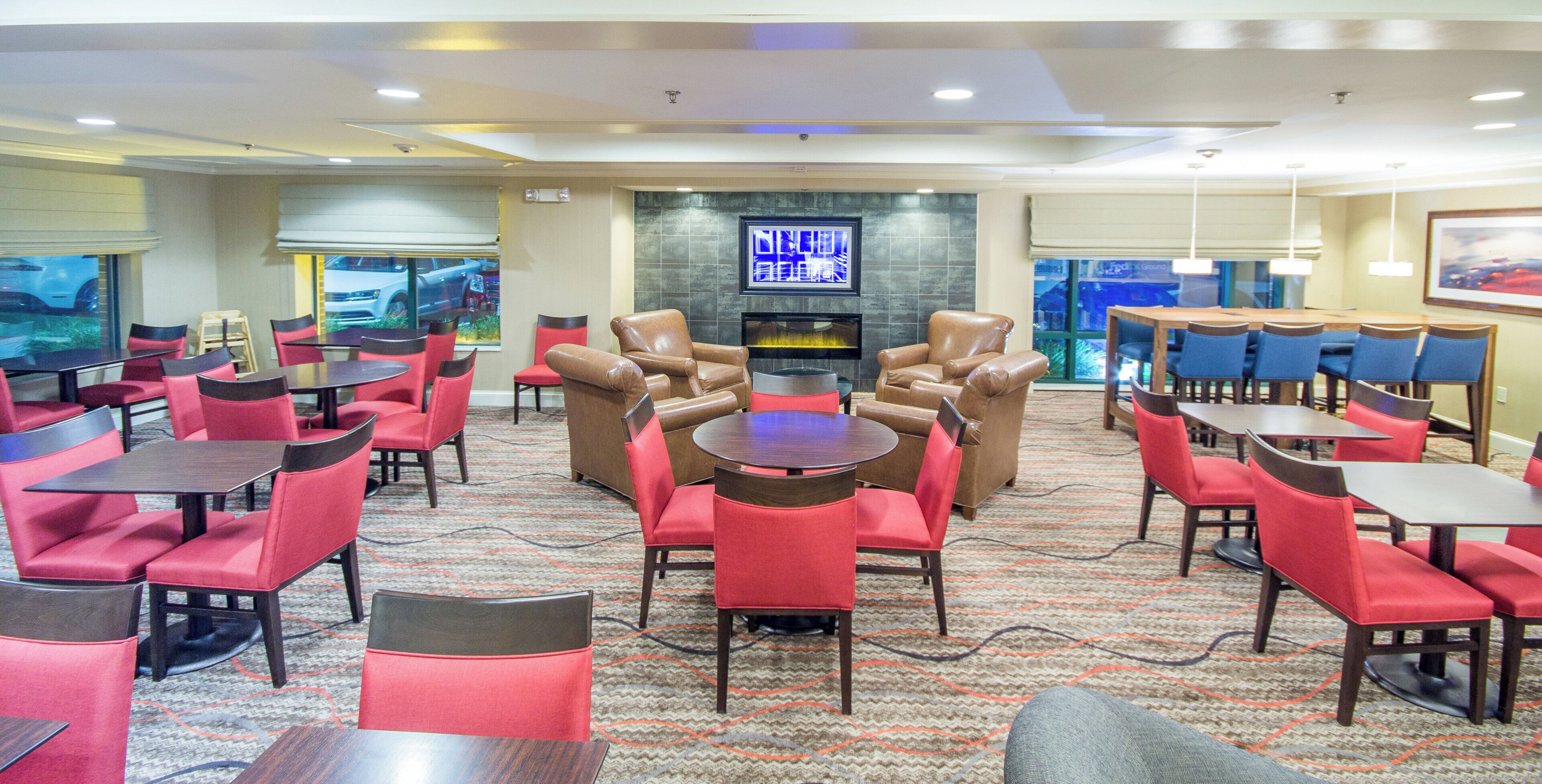 A hotel lobby with multiple seating areas, a fireplace, and a television screen.