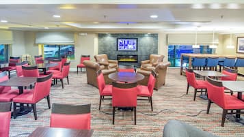 A hotel lobby with multiple seating areas, a fireplace, and a television screen.