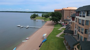 A lakeside hotel with a sandy beach, lounge chairs, and umbrellas. - SouthShore Hotel on Lake Bemidji, Trademark Coll by Wyndham (Bemidji)
