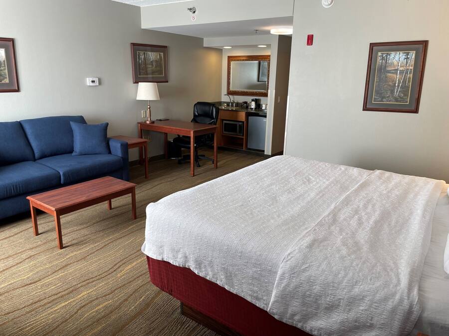 Una habitación de hotel con cama, sofá, escritorio y una silla.