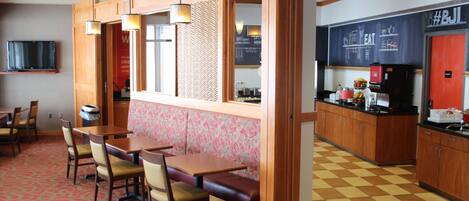 Un restaurante con mobiliario de madera, un muro con estampado y un suelo a cuadros.