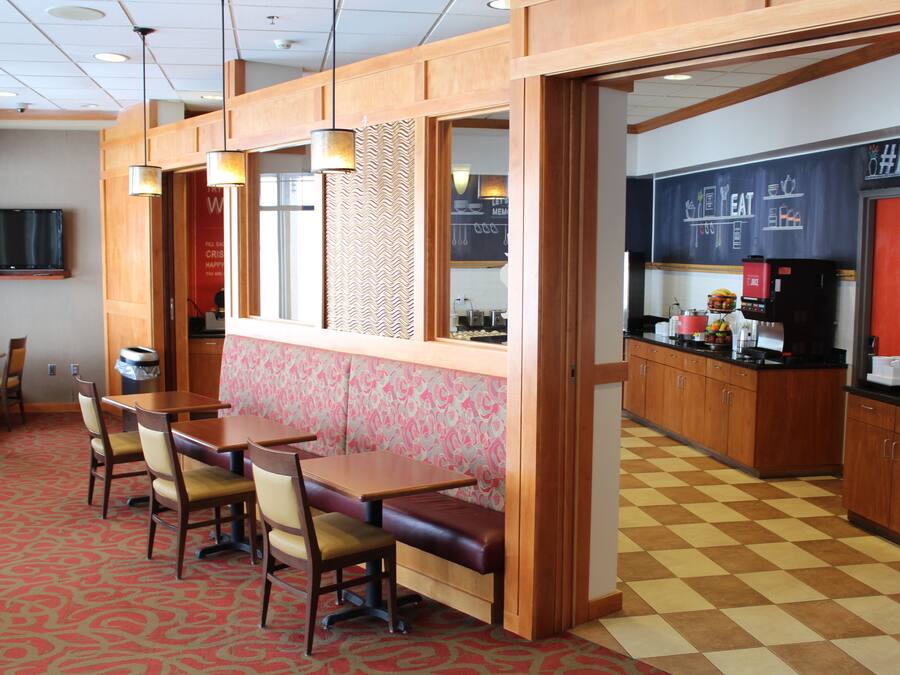 A restaurant with wooden furniture, a patterned wall, and a checkered floor.