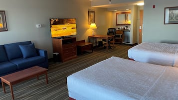 Une chambre d’hôtel avec deux lits, un canapé, une télévision, un bureau et une kitchenette.