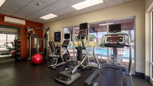 A gym with treadmills, elliptical machines, and exercise balls.