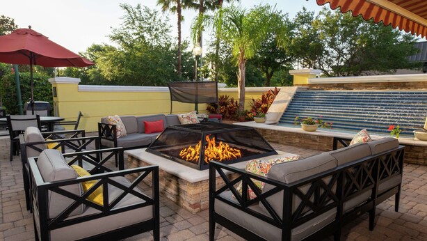 An outdoor patio with a fire pit, seating, and a water feature.