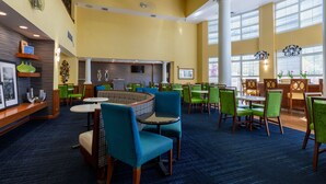 A hotel lobby with a curved seating area, multiple tables, and chairs.
