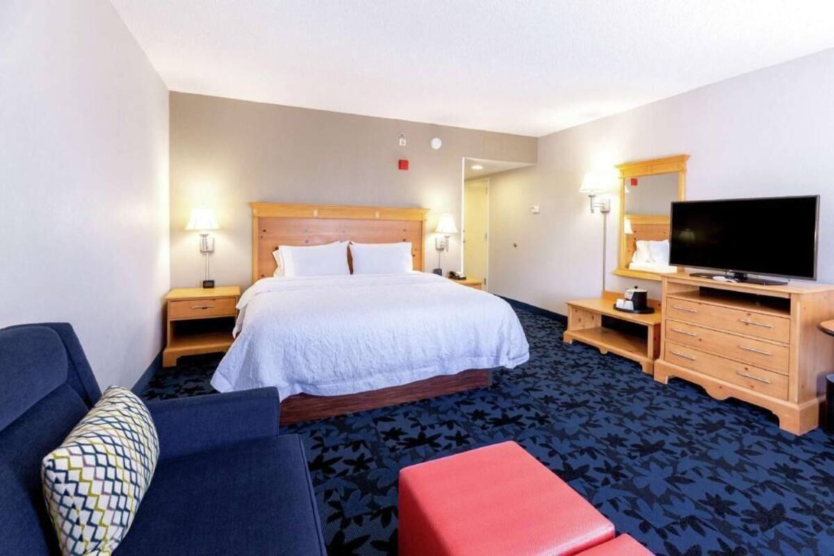 A hotel room with a bed, a television, a desk, and a chair.