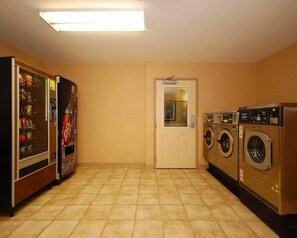 Un lavadero con máquina expendedora, una puerta y una lavadora.