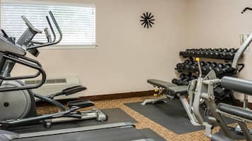Un gimnasio con cintas de correr, mancuernas y máquinas de pesas.