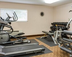 Un gimnasio con cintas de correr, mancuernas y máquinas de pesas.
