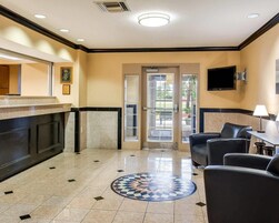 Un hall de hotel con mostrador de recepción, zona de estar y suelo estampado.