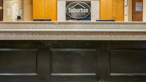 A reception desk with a sign for Suburban Extended Stay Hotel. - Suburban Studios Avondale (Westwego)