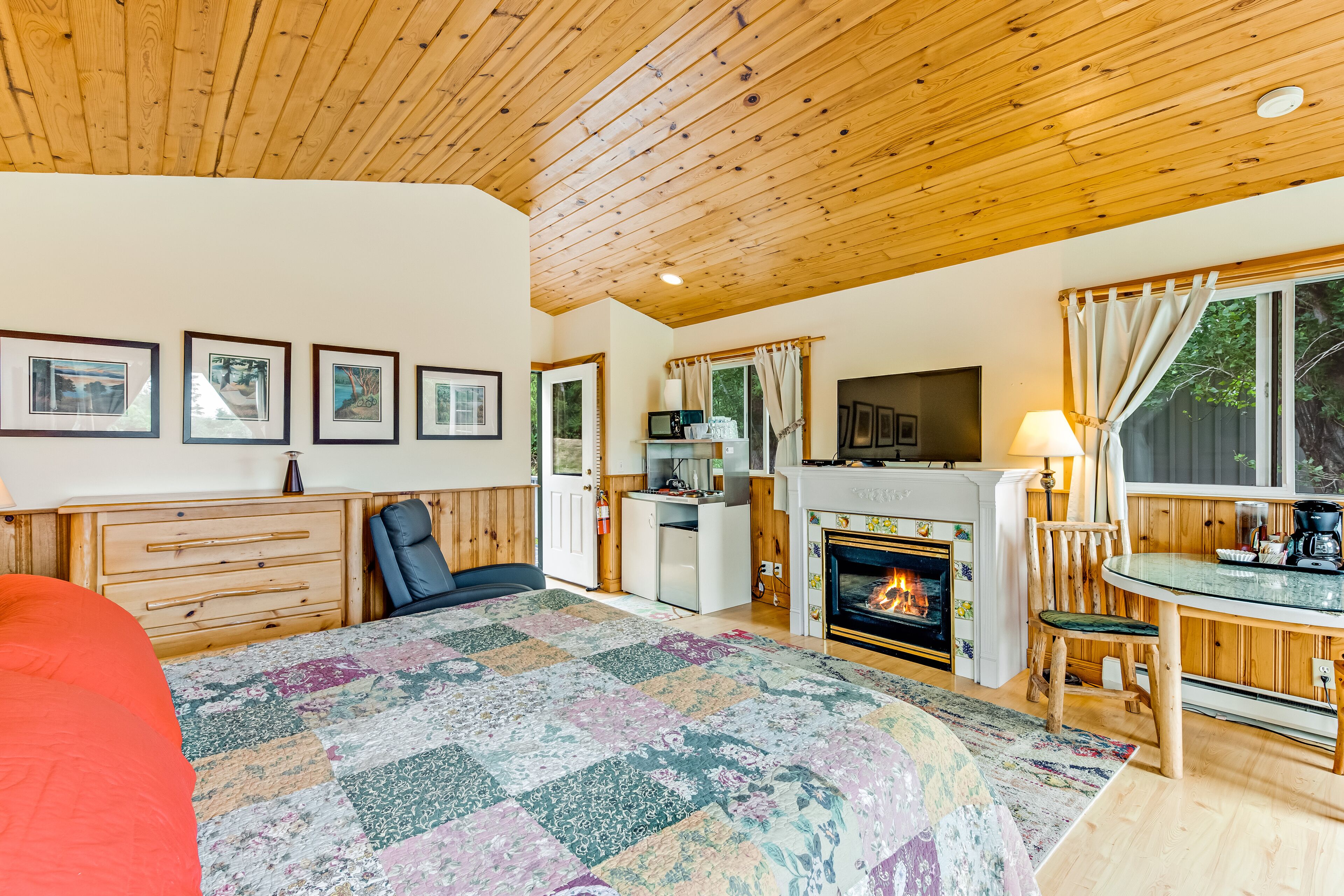 A cozy room with a bed, a fireplace, a TV, and a dining area.