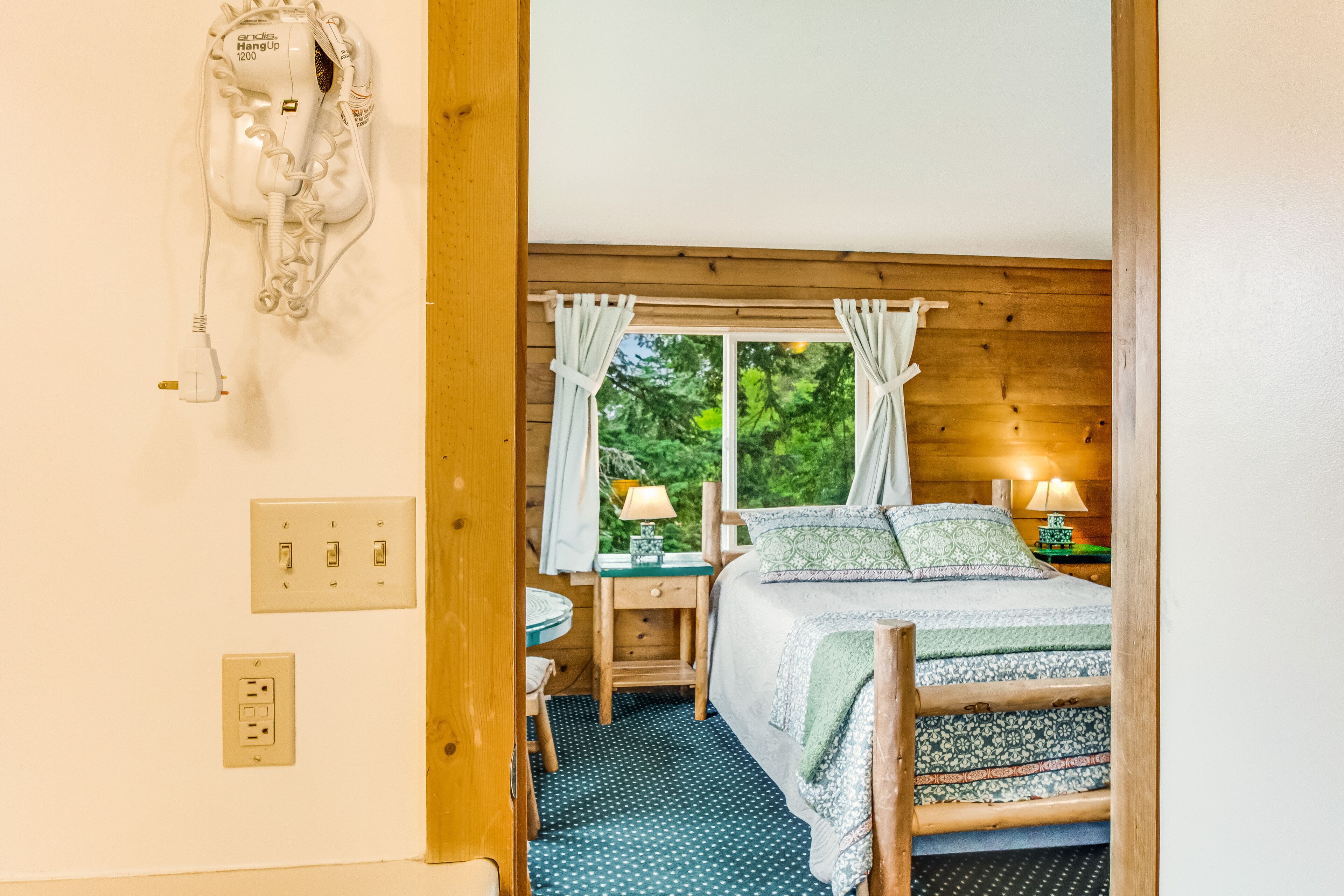Une chambre à coucher avec un lit, un bureau, une chaise, un téléphone et une fenêtre avec des rideaux.