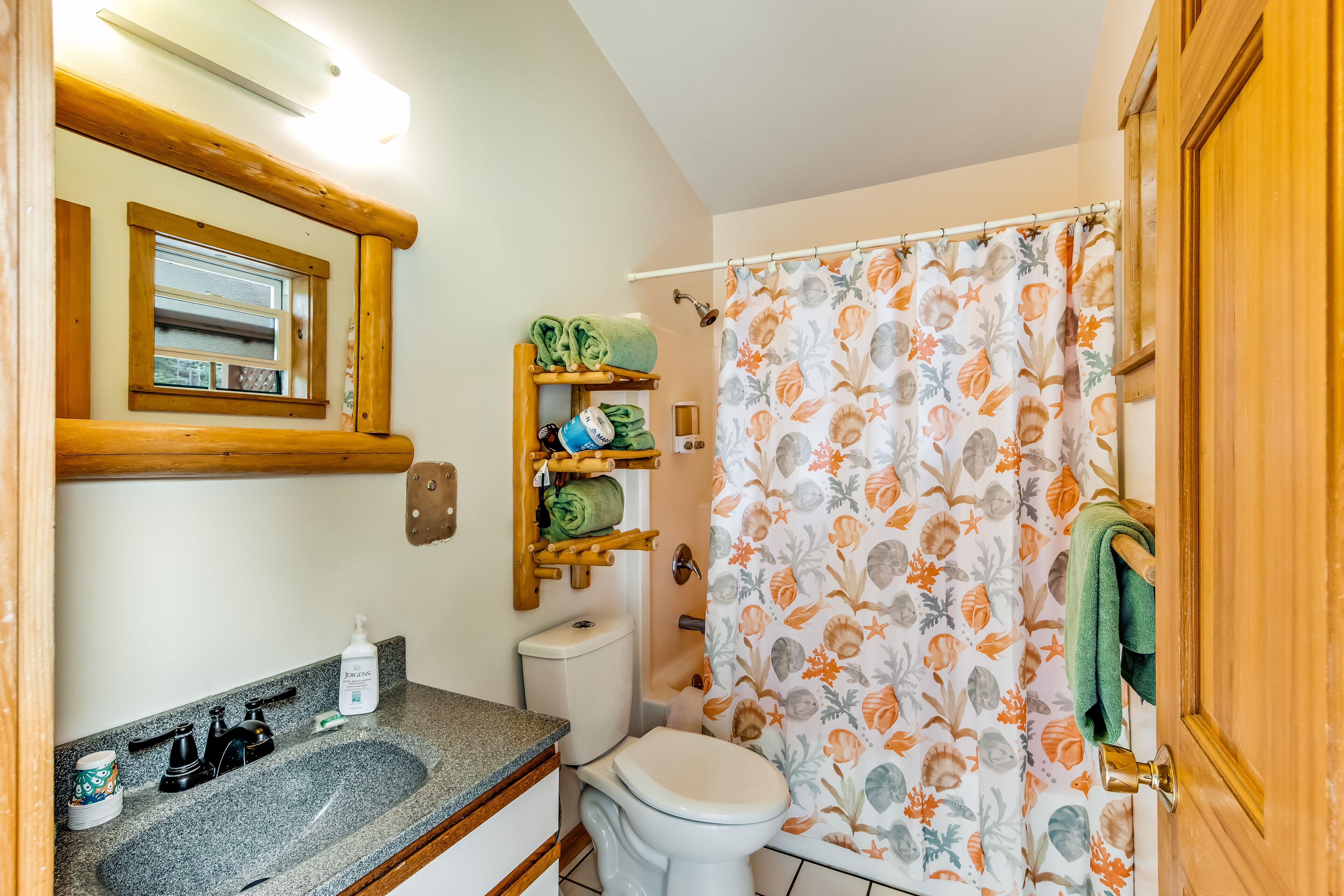 A bathroom with a granite sink, toilet, and shower curtain with a floral pattern.