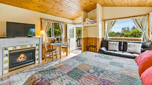 Una habitación acogedora con chimenea, televisión, zona de comedor y sofá con vistas a zonas verdes.