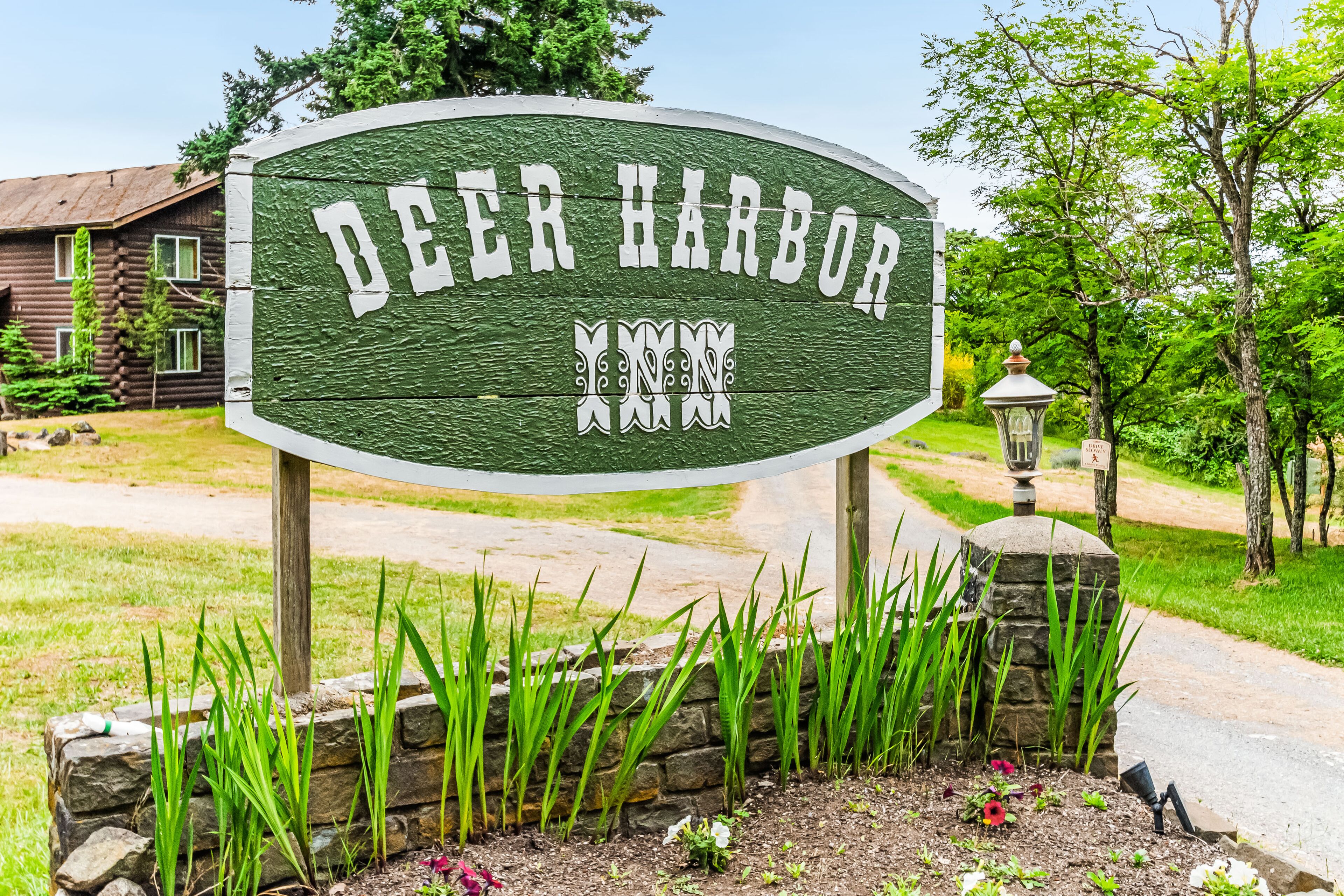 Schild für Deer Harbor, im Hintergrund ein rustikales Holzhaus.