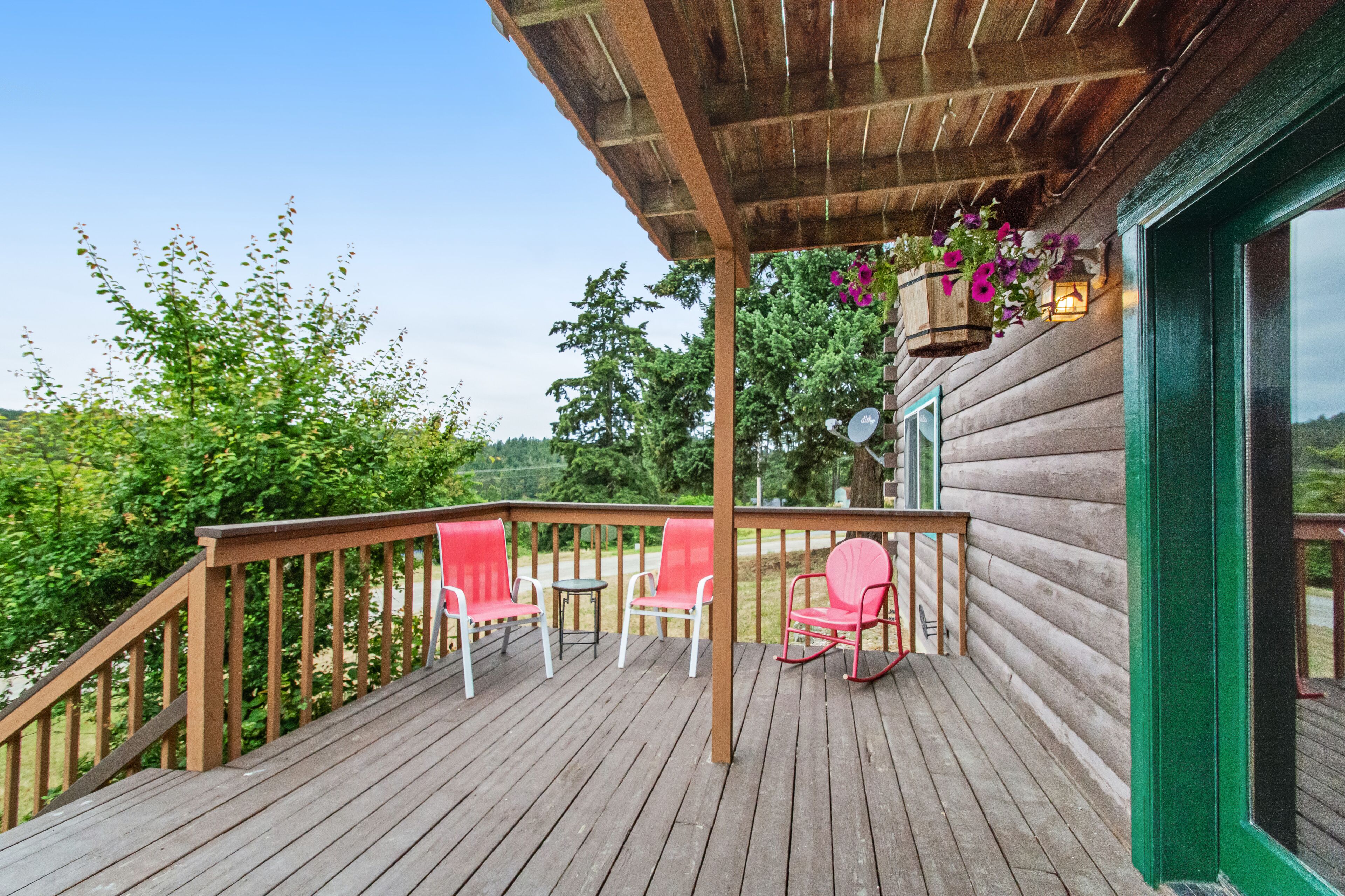 A wooden deck with red chairs and a hanging planter.