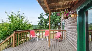 A wooden deck with red chairs and a hanging planter.