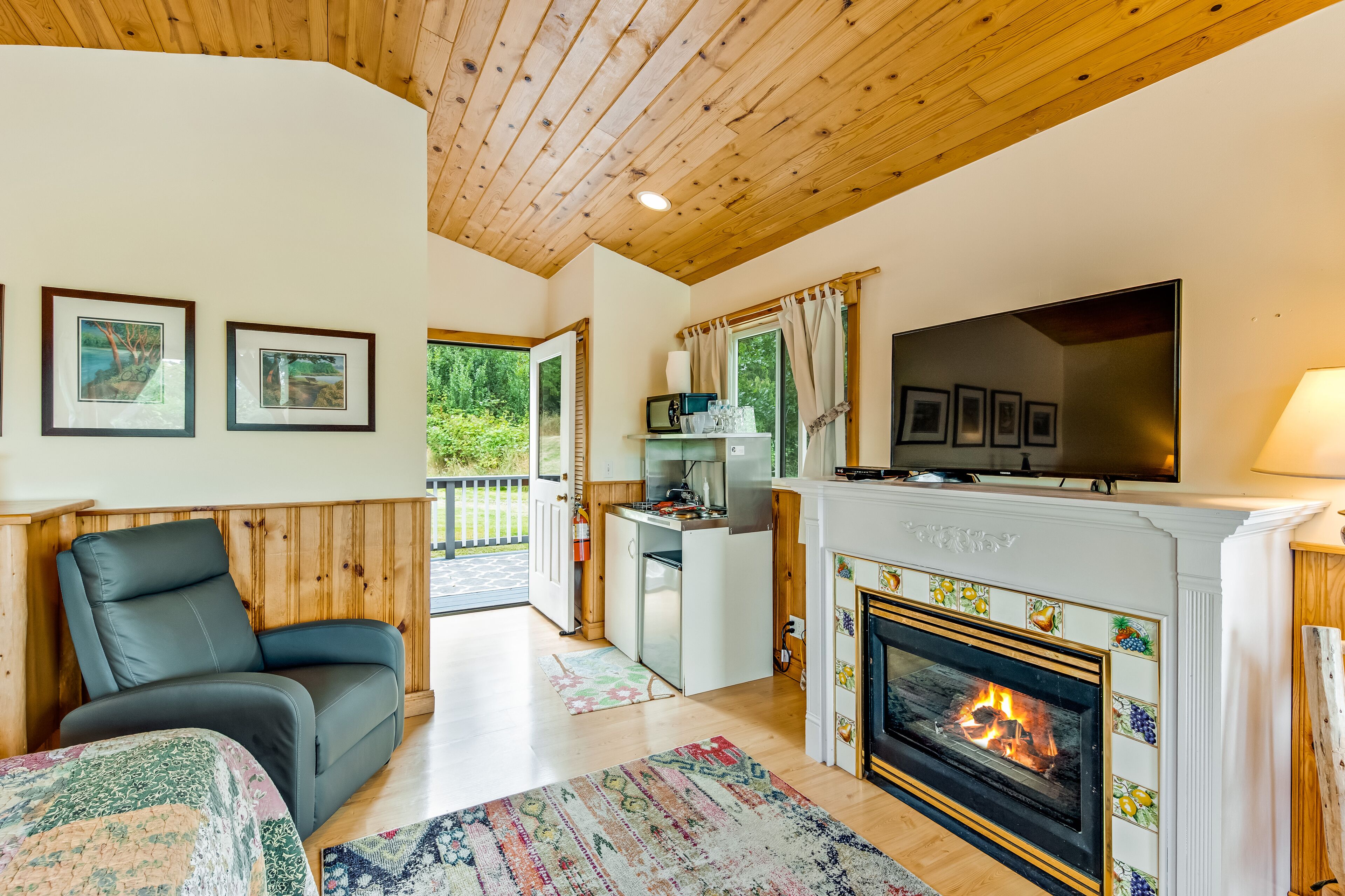 A cozy living room with a fireplace, a sofa, a television, and framed pictures on the wall.